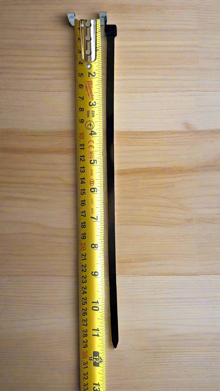 A 12-inch 120lb zip tie measured against a tape measure, demonstrating its precise length and robust design.