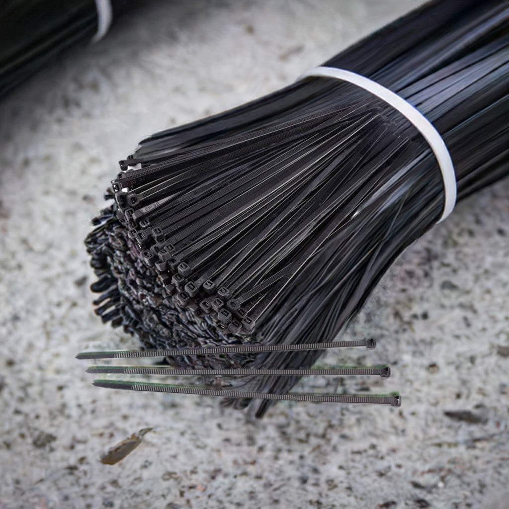 Bulk of 6-inch black heavy-duty zip ties in a 100-pack, displayed on a concrete surface, showcasing their durability and high tensile strength.